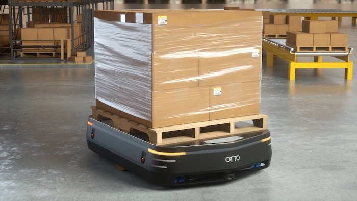 图中是一个奥托工业机器人在仓库环境中扛着一大堆箱子。